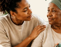 A woman with her hand on her elderly mother's shoulder